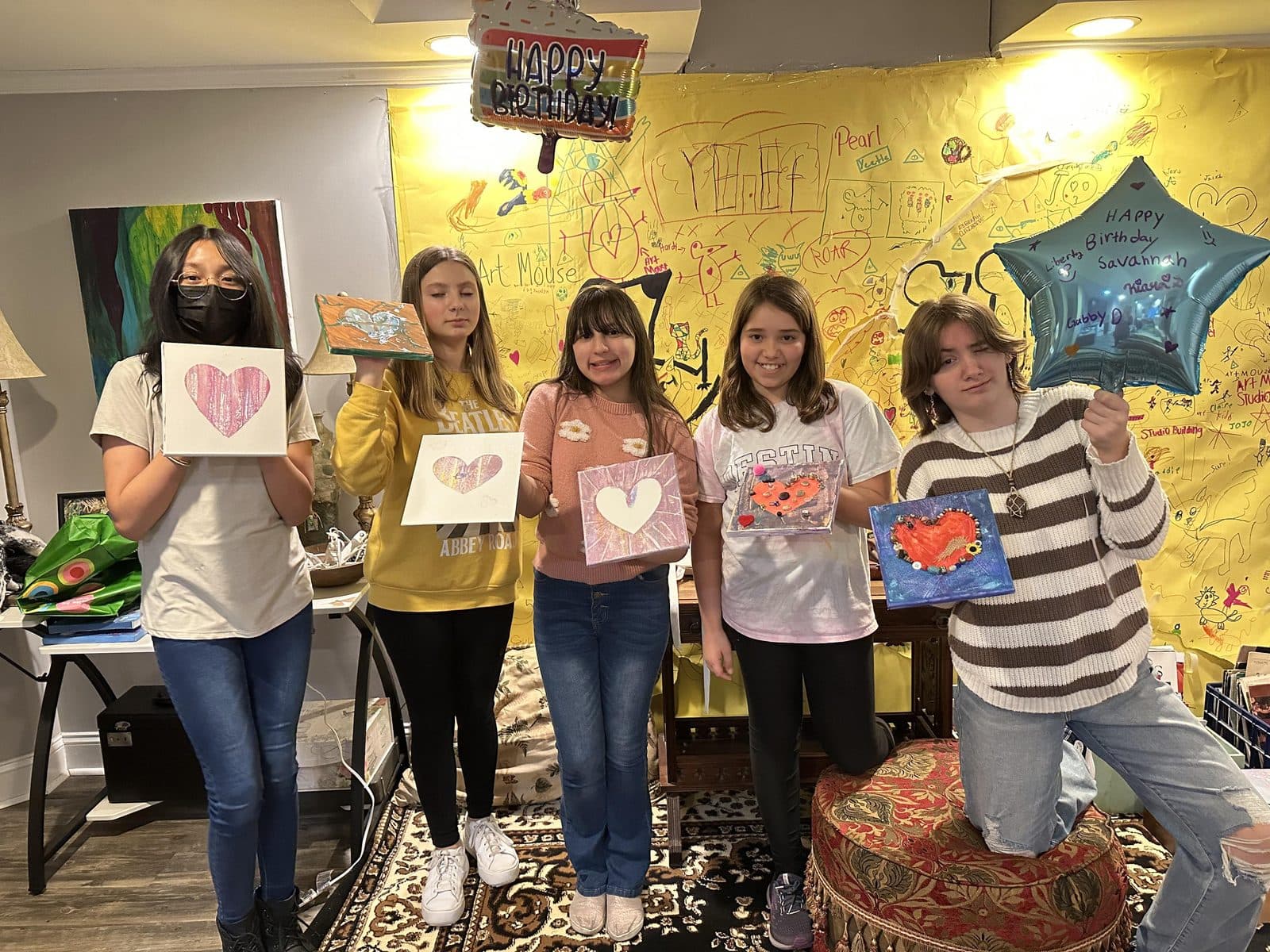 A party group holding up their finished heart paintings together