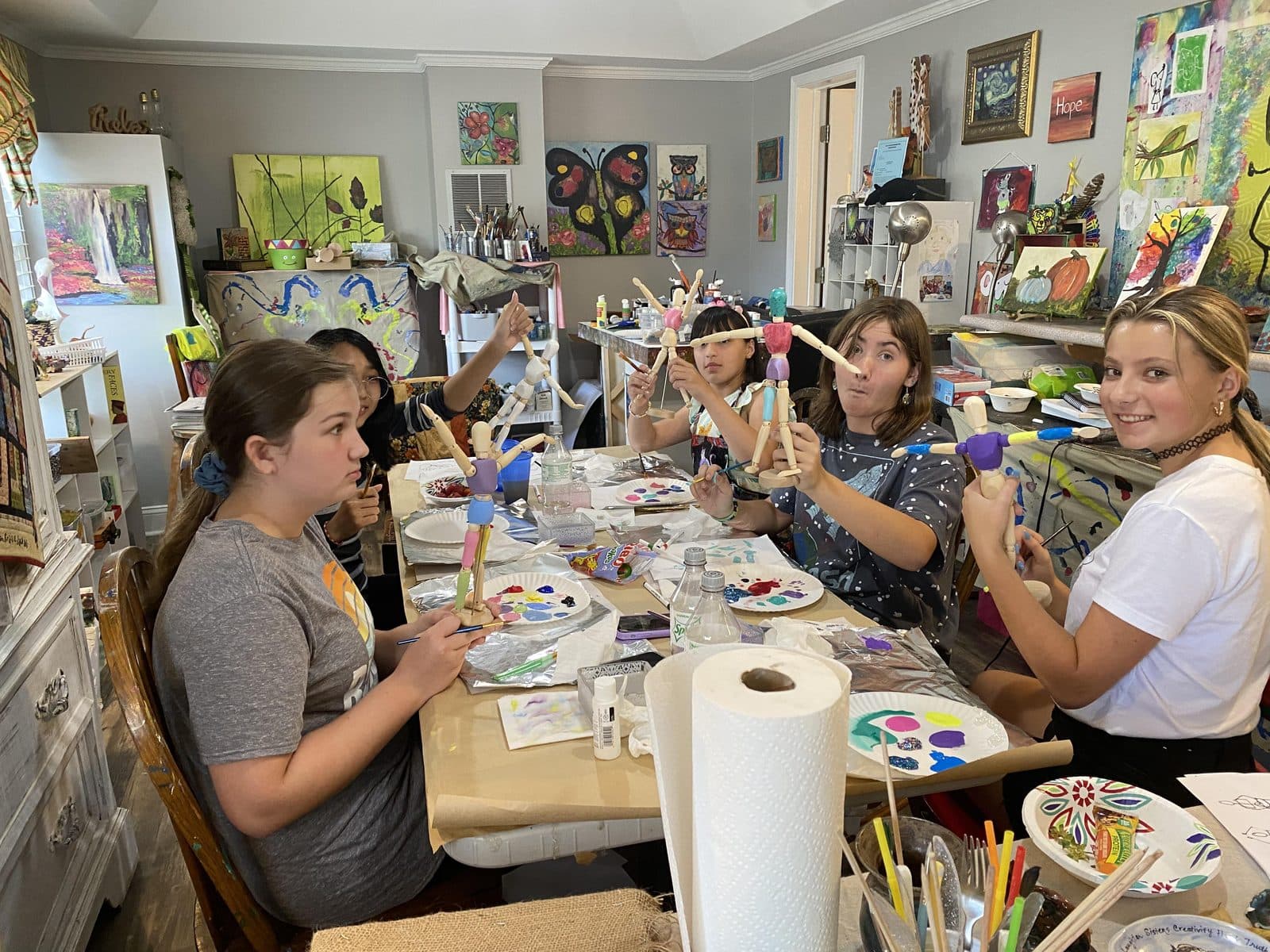 Friends painting side by side at the party table