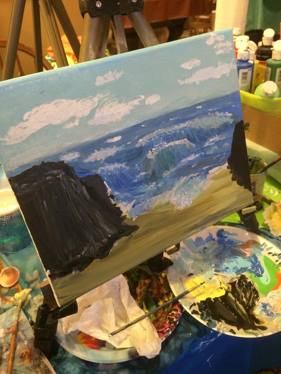 A seascape on the easel beside its palette
