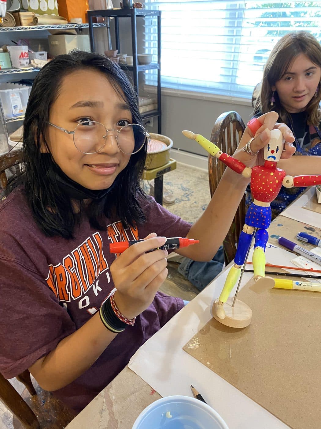 Two students painting wooden figures